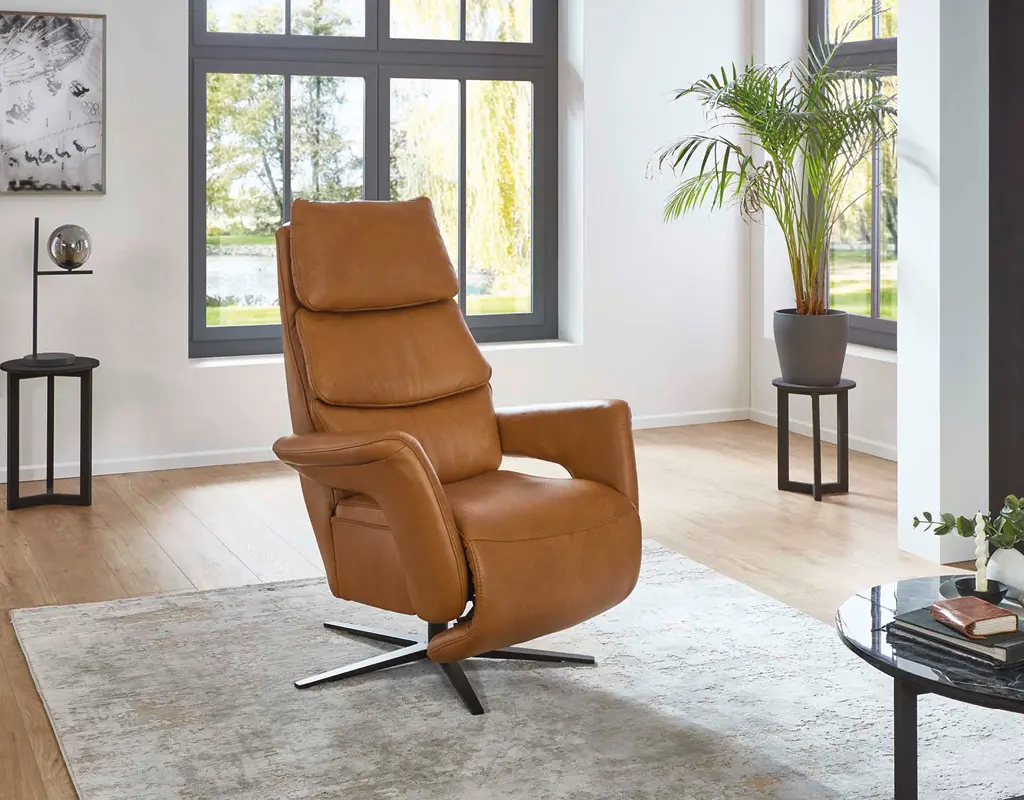 Moderner brauner Ledersessel in hellem Wohnzimmer mit großen Fenstern, Teppich und Pflanzen. Bequemer Relaxsessel als hochwertiges Polstermöbel für stilvolle Wohnzimmereinrichtung.